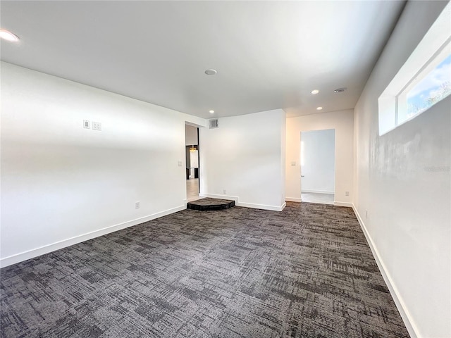 spare room featuring dark colored carpet, visible vents, baseboards, and recessed lighting