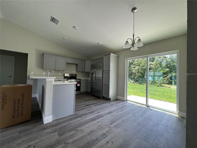 kitchen featuring lofted ceiling, a notable chandelier, kitchen peninsula, stainless steel appliances, and gray cabinetry