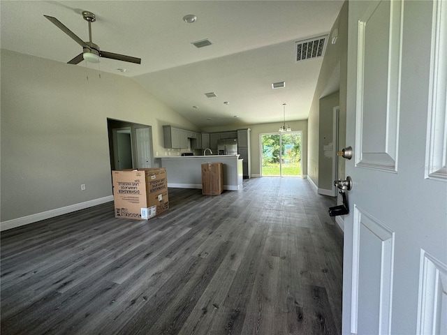 interior space featuring vaulted ceiling, ceiling fan with notable chandelier, and dark hardwood / wood-style flooring