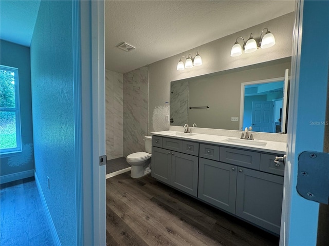 bathroom with wood-type flooring, a wealth of natural light, vanity, and a textured ceiling