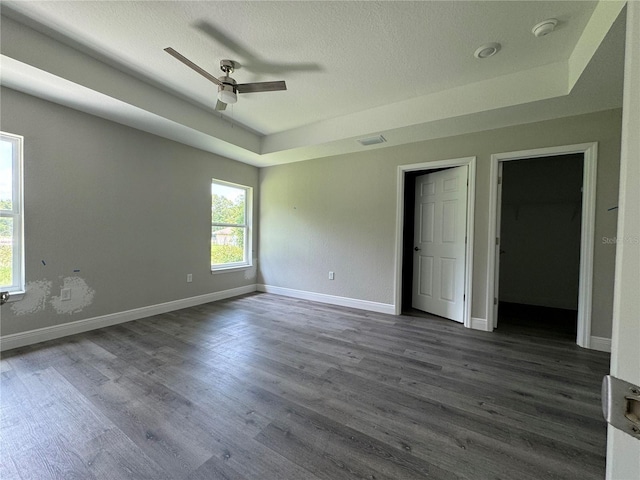 unfurnished room with dark wood-type flooring, ceiling fan, and a raised ceiling