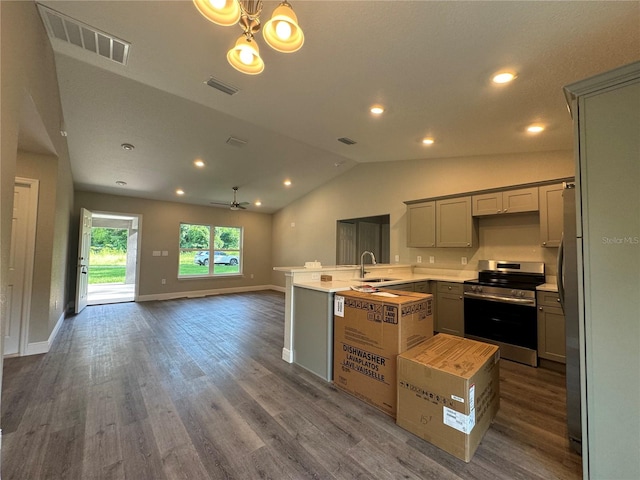 kitchen featuring kitchen peninsula, dark hardwood / wood-style floors, stainless steel appliances, vaulted ceiling, and sink