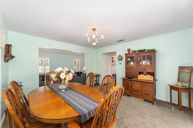 dining area featuring light colored carpet and a notable chandelier