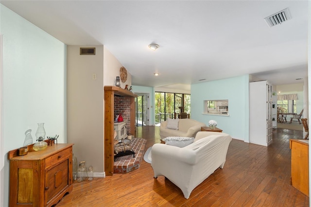 living room featuring a brick fireplace and wood-type flooring