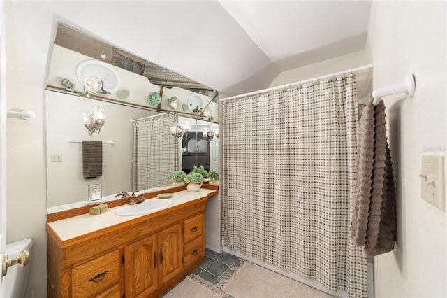 bathroom with lofted ceiling, vanity, tile patterned floors, and toilet