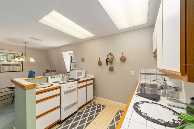 kitchen featuring tile countertops, sink, white appliances, white cabinetry, and hanging light fixtures