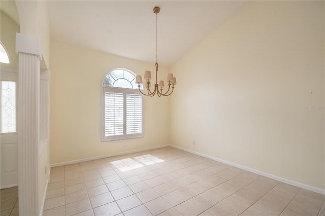 tiled empty room with a healthy amount of sunlight, high vaulted ceiling, and an inviting chandelier