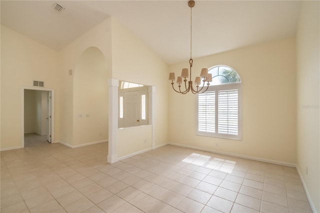 empty room with high vaulted ceiling, light tile patterned floors, and an inviting chandelier