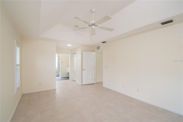 spare room featuring ceiling fan, a raised ceiling, and light tile patterned floors