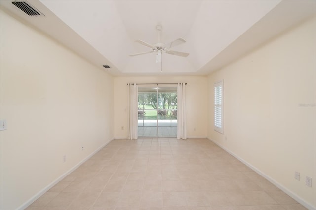 empty room with light tile patterned floors, a raised ceiling, and ceiling fan