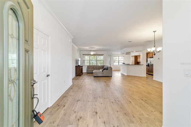 unfurnished living room featuring crown molding, light hardwood / wood-style flooring, and ceiling fan with notable chandelier