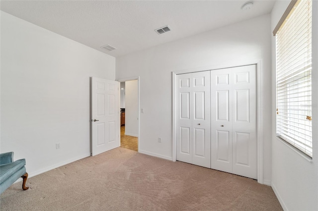 unfurnished bedroom with light carpet and a closet