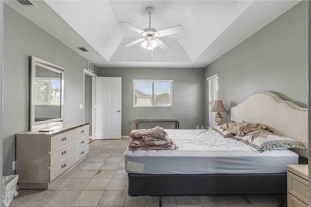 tiled bedroom featuring a tray ceiling and ceiling fan