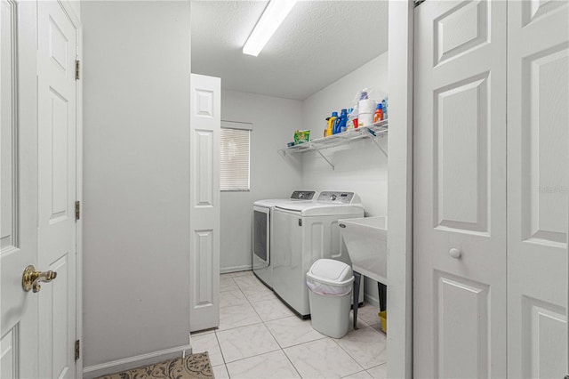 laundry area featuring separate washer and dryer, light tile patterned flooring, and a textured ceiling