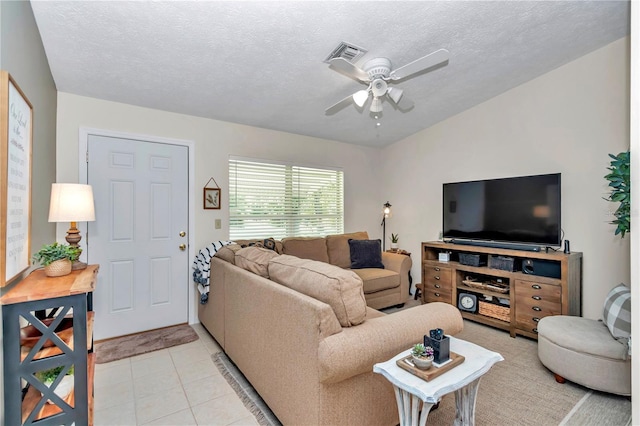 living room with a textured ceiling, ceiling fan, and light tile patterned flooring