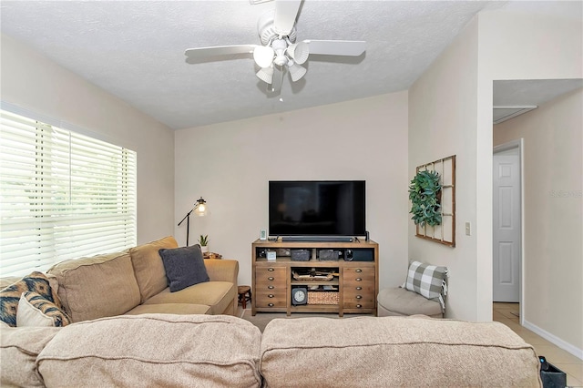 living room with ceiling fan, a textured ceiling, and light tile patterned floors