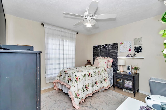 tiled bedroom with ceiling fan and a textured ceiling