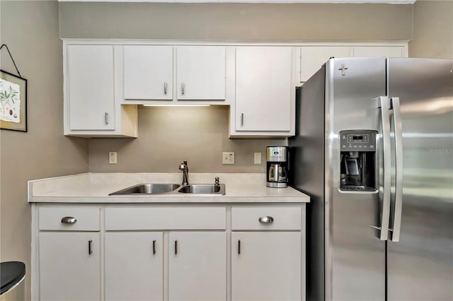 kitchen with stainless steel refrigerator with ice dispenser, sink, and white cabinetry