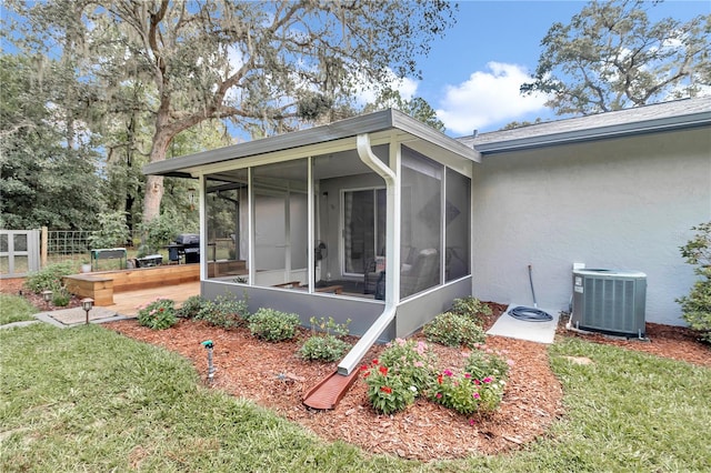 view of property exterior with central AC, a sunroom, and a lawn