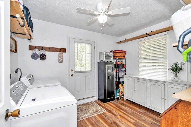 clothes washing area with a textured ceiling, cabinets, independent washer and dryer, and light hardwood / wood-style flooring