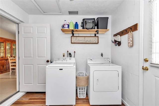 clothes washing area featuring a textured ceiling, independent washer and dryer, and light wood-type flooring