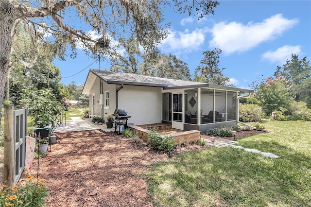 rear view of property featuring a yard, a patio, and a sunroom