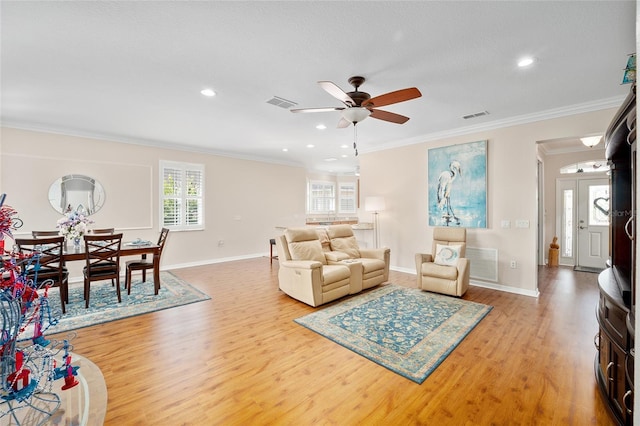 living room featuring light wood-type flooring, a wealth of natural light, crown molding, and ceiling fan