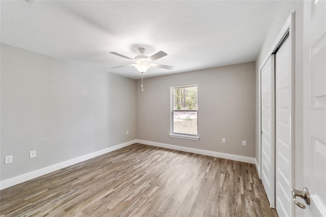 unfurnished bedroom featuring a textured ceiling, light hardwood / wood-style flooring, a closet, and ceiling fan