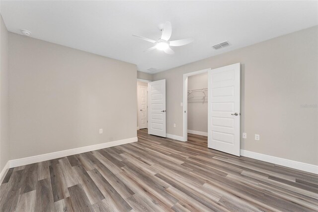 4444 SW 118th Ter, Ocala, FL 34481 - unfurnished bedroom featuring wood finished floors, baseboards, a closet, a spacious closet, and a ceiling fan