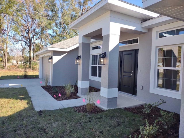 view of exterior entry with a garage and a lawn