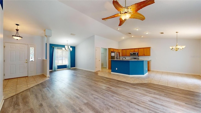 kitchen featuring appliances with stainless steel finishes, light wood-type flooring, vaulted ceiling, ceiling fan with notable chandelier, and decorative light fixtures