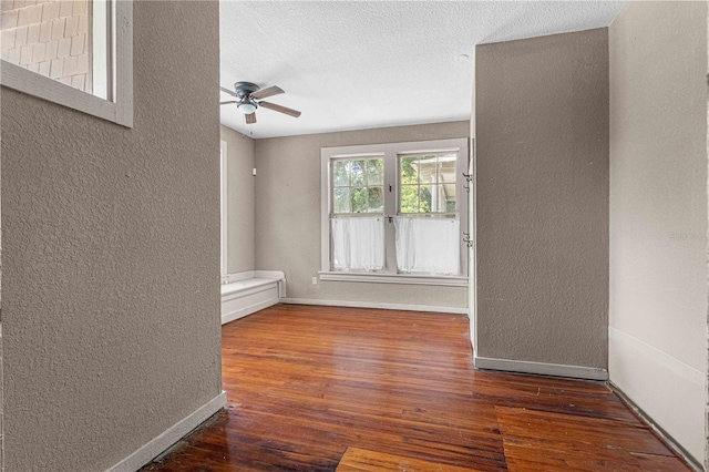 empty room with ceiling fan, dark hardwood / wood-style flooring, and a textured ceiling