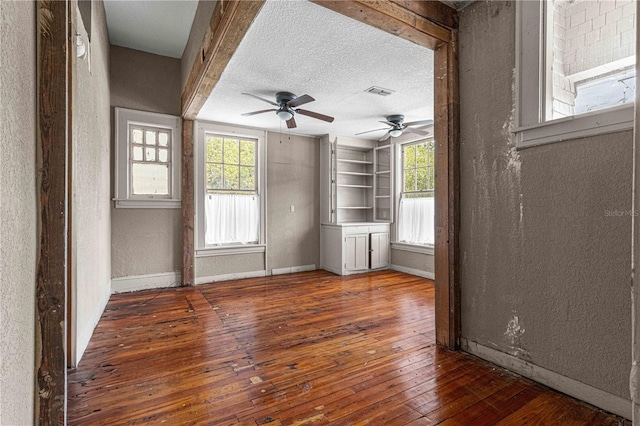 empty room with plenty of natural light, a textured ceiling, and dark hardwood / wood-style flooring