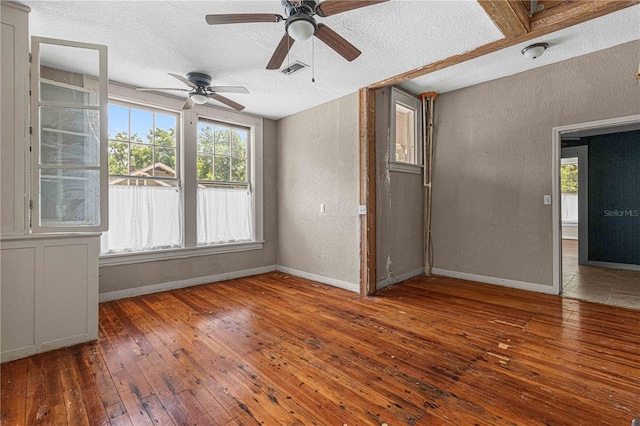 unfurnished room with a wealth of natural light, wood-type flooring, and a textured ceiling