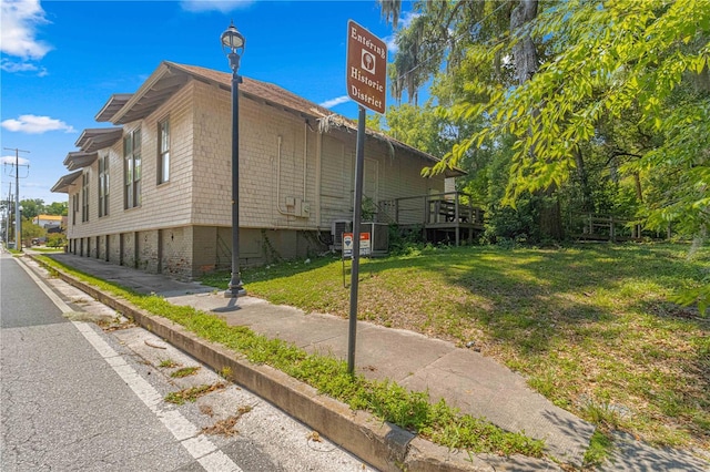 view of side of property with central AC and a lawn