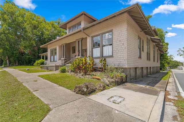 view of property exterior with a porch and a lawn