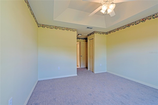 unfurnished room with carpet floors, ceiling fan, and a tray ceiling