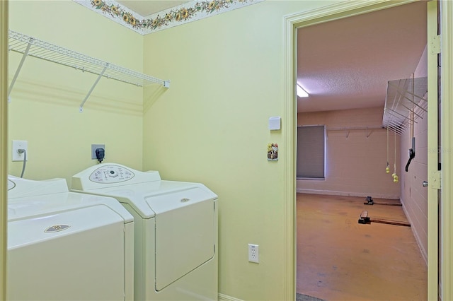 clothes washing area with washing machine and dryer and a textured ceiling