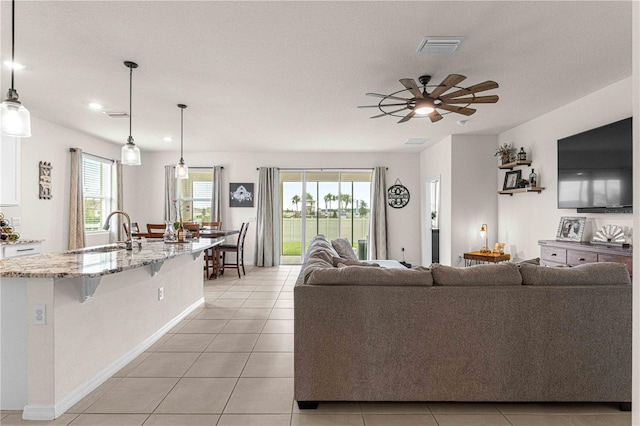 living room featuring sink, light tile patterned floors, and ceiling fan