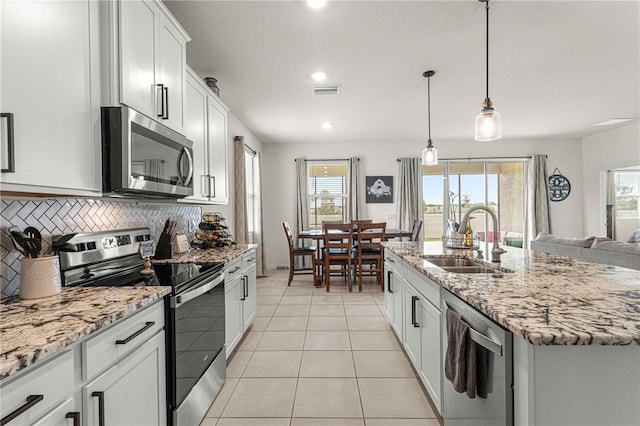 kitchen featuring appliances with stainless steel finishes, an island with sink, decorative light fixtures, sink, and white cabinetry