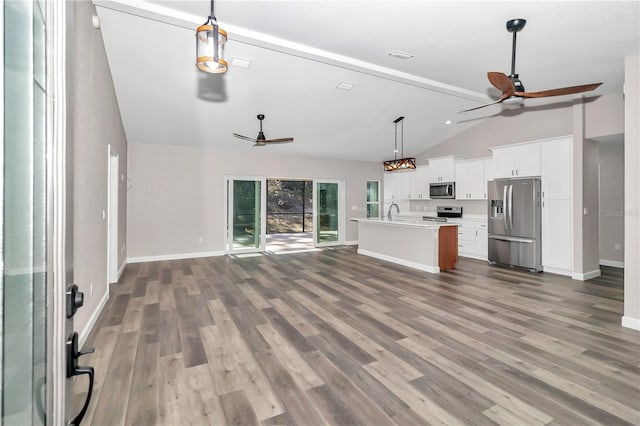 unfurnished living room with vaulted ceiling with beams, hardwood / wood-style floors, and sink