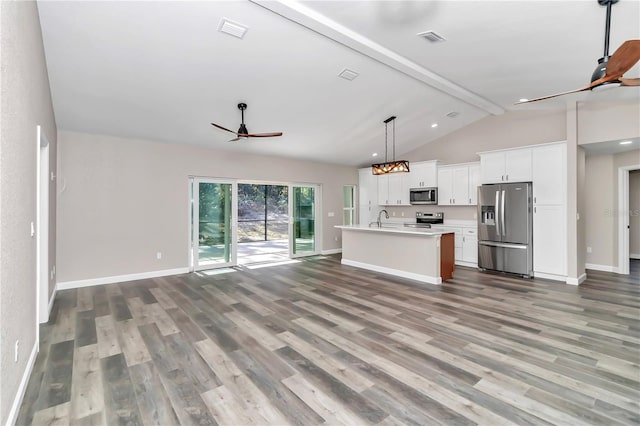 kitchen with appliances with stainless steel finishes, a kitchen island with sink, ceiling fan, vaulted ceiling with beams, and hanging light fixtures