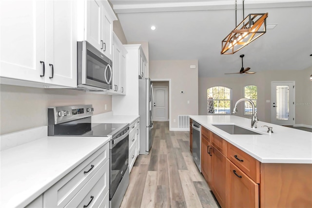 kitchen featuring stainless steel appliances, ceiling fan, sink, white cabinetry, and an island with sink