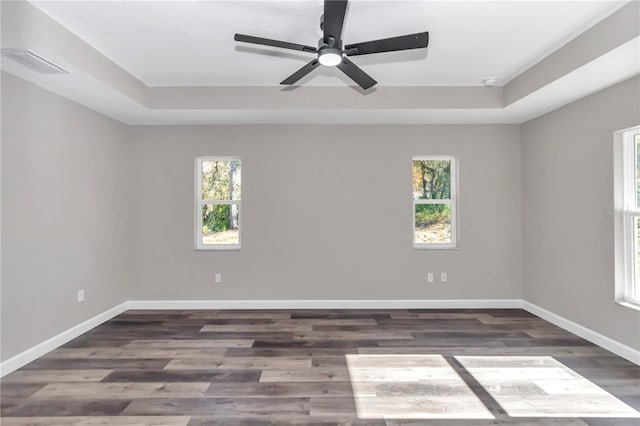 unfurnished room featuring a tray ceiling, dark hardwood / wood-style floors, and ceiling fan