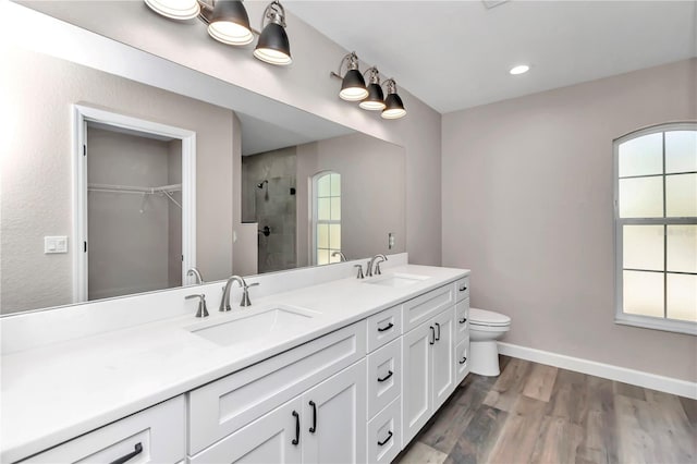 bathroom featuring hardwood / wood-style flooring, vanity, toilet, and a tile shower