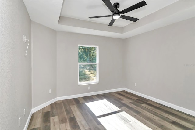 unfurnished room with dark hardwood / wood-style floors, ceiling fan, and a tray ceiling