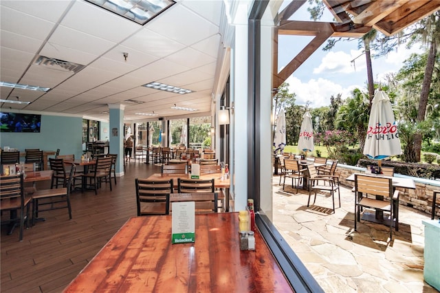 dining space with a paneled ceiling and hardwood / wood-style flooring