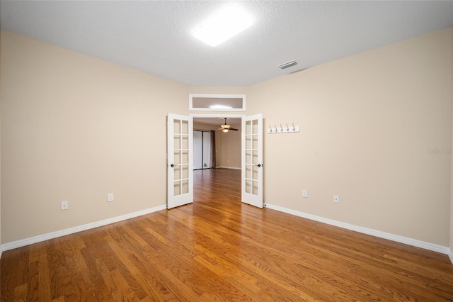 unfurnished room with french doors, ceiling fan, hardwood / wood-style floors, and a textured ceiling