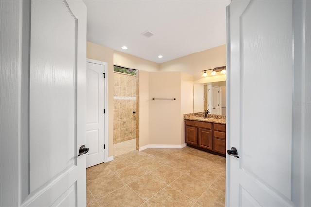 bathroom featuring tile patterned flooring, vanity, and a tile shower