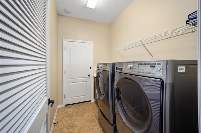 clothes washing area with light tile patterned flooring and washing machine and clothes dryer